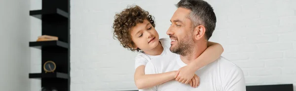 Colpo panoramico di riccio figlio abbracciare felice padre barbuto in camera da letto — Foto stock