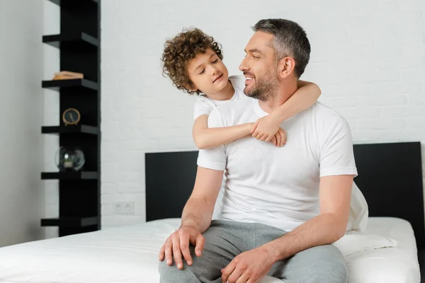 Fils bouclé câlin joyeux père barbu dans la chambre — Photo de stock