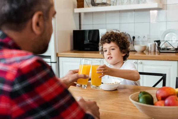 Selective focus of father and son clinking glasses of orange juice — Stock Photo