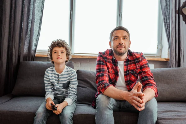 Guapo padre y lindo hijo viendo película en sala de estar - foto de stock