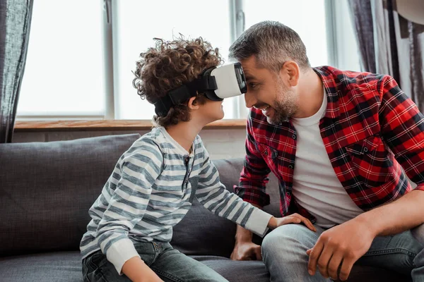 Fröhlicher Vater neben lockigem Sohn im Virtual-Reality-Headset — Stockfoto
