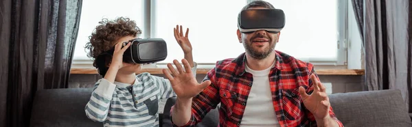 Coltura orizzontale di padre barbuto e figlio riccio in cuffie realtà virtuale — Foto stock