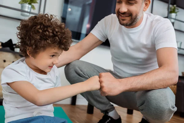 Fröhlicher Vater schlägt daheim mit lächelndem Sohn die Fäuste — Stockfoto