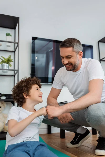 Glücklicher Vater schlägt daheim mit lächelndem Sohn die Fäuste — Stockfoto