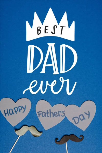 Вид зверху на декоративні чорні вуса і папір нарізані сірими серцями з написом щасливі батьки день на синьому фоні, кращий тато коли-небудь ілюстрація — стокове фото