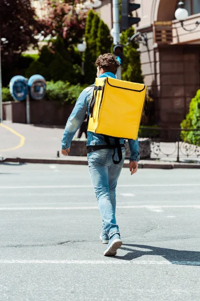 Visão traseira do correio com mochila térmica andando na passarela — Fotografia de Stock