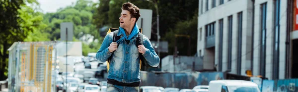 Panoramic shot of handsome delivery man with thermo backpack on urban street — Stock Photo