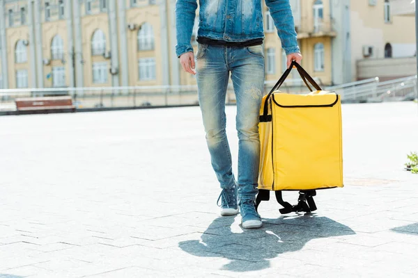 Cropped view of courier holding thermo bag on urban street at daytime — Stock Photo