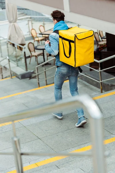 Вибірковий фокус доставки людини з термальним рюкзаком, що йде по сходах — стокове фото