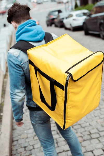 Vue arrière du courrier avec sac à dos thermique marchant sur le trottoir en pavé dans la rue urbaine — Photo de stock