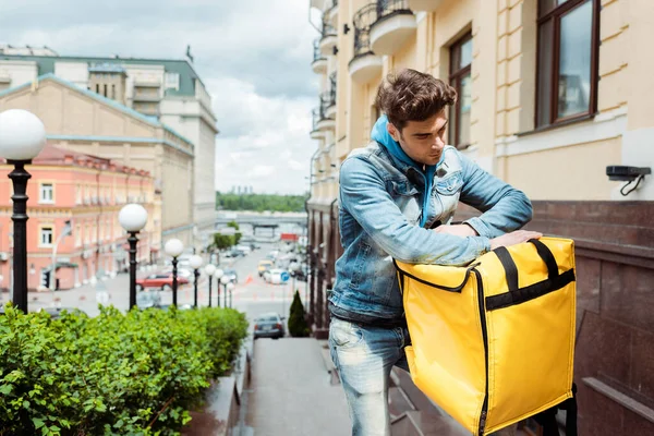 Courier holding thermo bag on urban street — Stock Photo