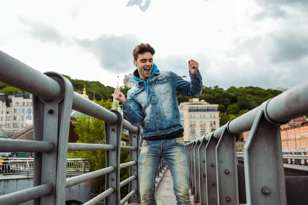 Foco seletivo de homem positivo em fones de ouvido dançando na ponte — Fotografia de Stock