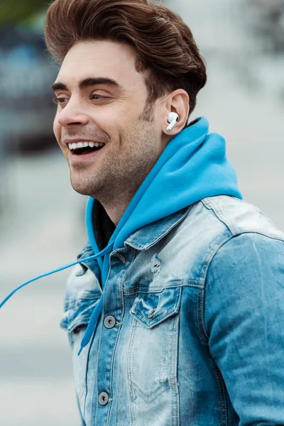 Homme souriant dans les écouteurs regardant loin à l'extérieur — Photo de stock