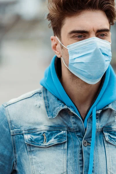 Молодий чоловік в медичній масці дивиться на відкритому повітрі — стокове фото