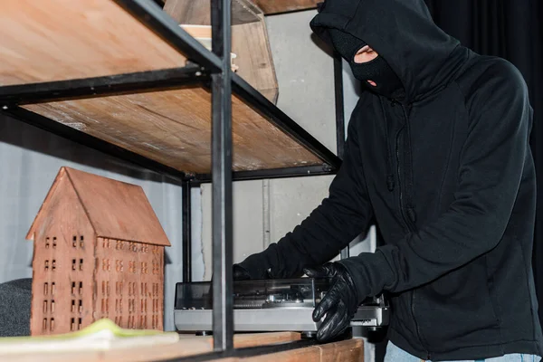 Concentration sélective du voleur dans la cagoule en prenant un tourne-disque pendant le vol — Photo de stock