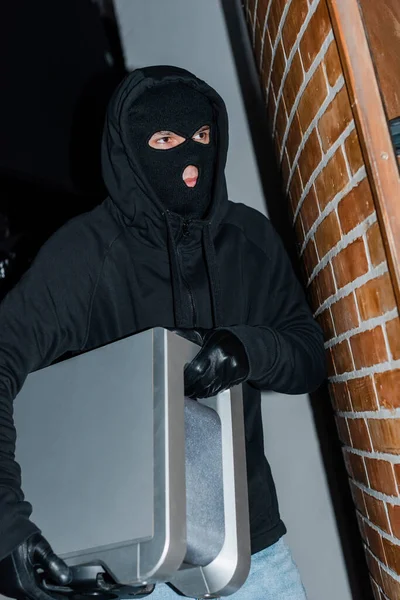 Thief in mask and leather gloves holding wireless speaker during robbery — Stock Photo