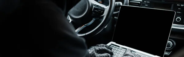 Panoramic crop of robber using laptop in car — Stock Photo