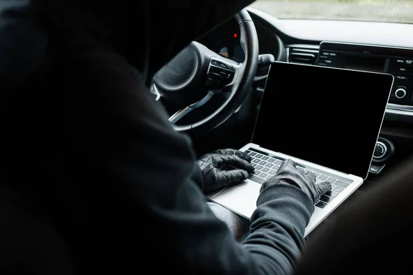 Concentration sélective du voleur dans les gants en cuir à l'aide d'un ordinateur portable dans la voiture — Photo de stock