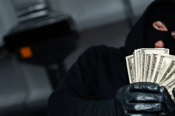 Selective focus of thief in leather gloves holding dollars — Stock Photo