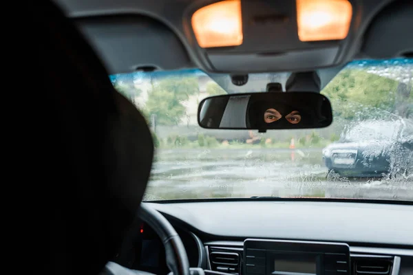 Foco seletivo do homem em balaclava olhando para o espelho no carro — Fotografia de Stock