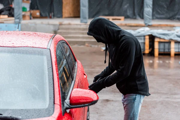 Side view of robber using screwdriver while opening car door on urban street — Stock Photo