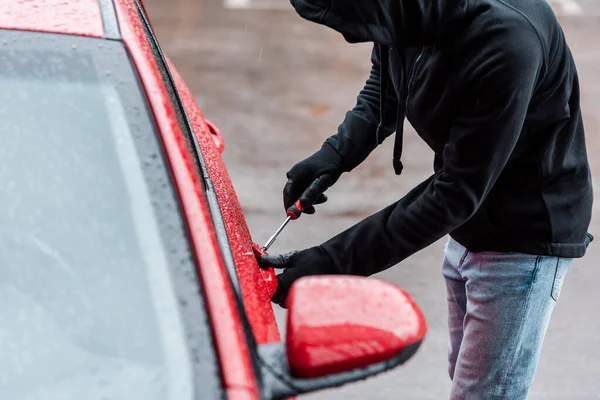 Side view of theft using screwdriver for lock on car door — Stock Photo