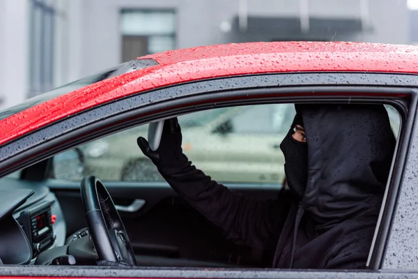 Side view of thief adjusting mirror while sitting in car — Stock Photo