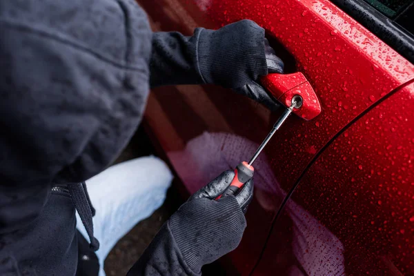 Overhead view of robber opening lock on door of car with screwdriver on urban street — Stock Photo