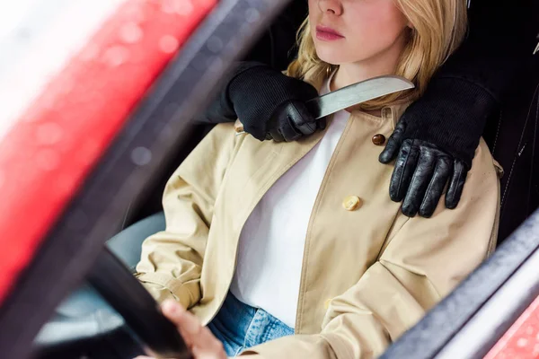 Foco seletivo do ladrão segurando faca perto do pescoço da mulher no carro — Fotografia de Stock
