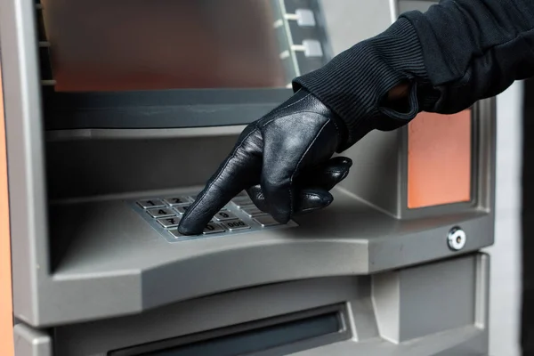 Vista cortada de ladrão em luva de couro usando atm — Fotografia de Stock