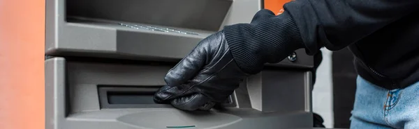 Panoramic crop of burglar holding hand near cash dispenser of atm — Stock Photo