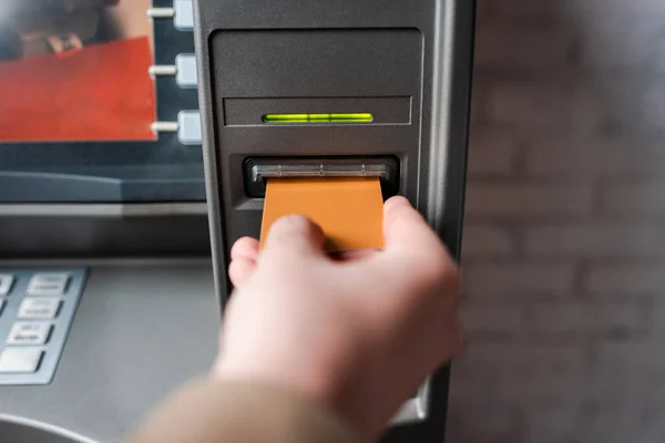 Ausgeschnittene Ansicht eines Mannes, der Kreditkarte hält, während er Geldautomat benutzt — Stockfoto