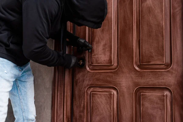 Side view of housebreaker using screwdriver while opening door lock — Stock Photo