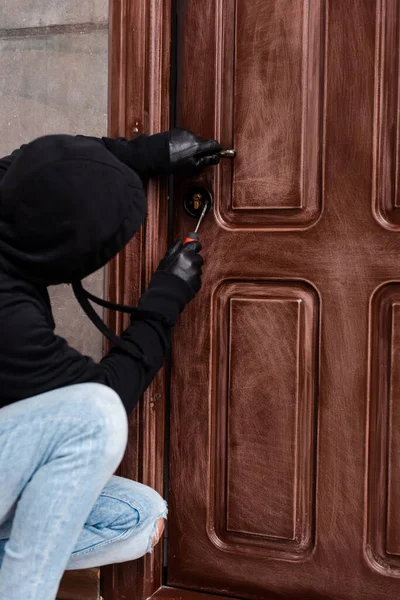 Side view of housebreaker opening door lock with screwdriver — Stock Photo