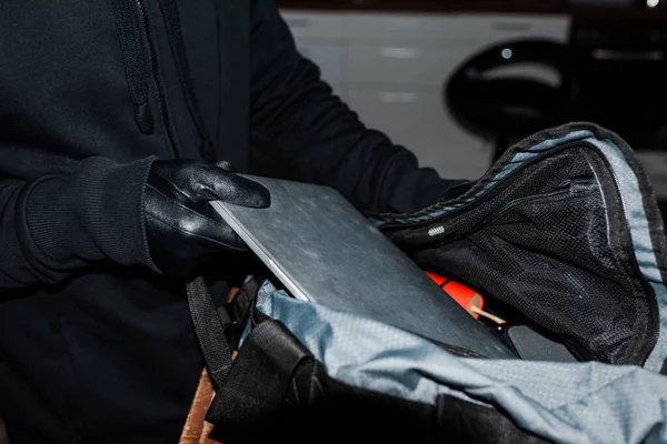 Vista recortada de ladrón poner portátil en bolsa con dinamita - foto de stock
