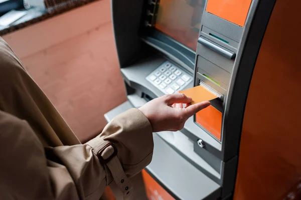 Vista recortada de la mujer que sostiene la tarjeta de crédito mientras usa cajero automático - foto de stock