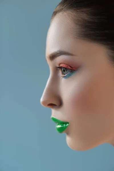 Портрет красивой женщины с зелеными губами, розовый и синий тени для век изолированы на синий — стоковое фото