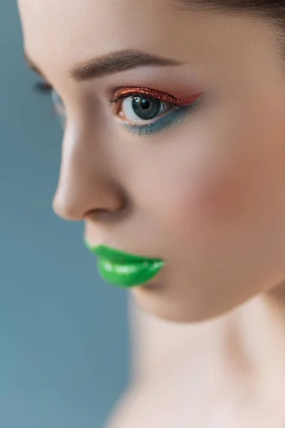 Portrait of beautiful woman with green lips, pink and blue eyeshadow isolated on blue, selective focus — Stock Photo