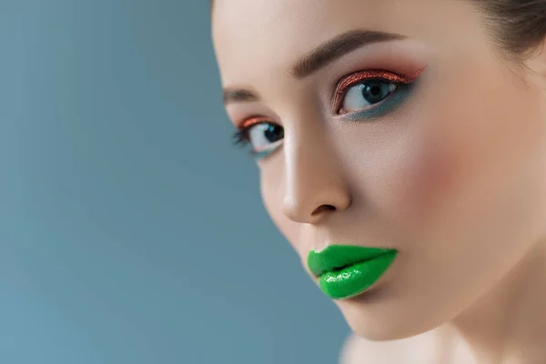 Portrait of beautiful woman with green lips, pink and blue eyeshadow isolated on blue — Stock Photo
