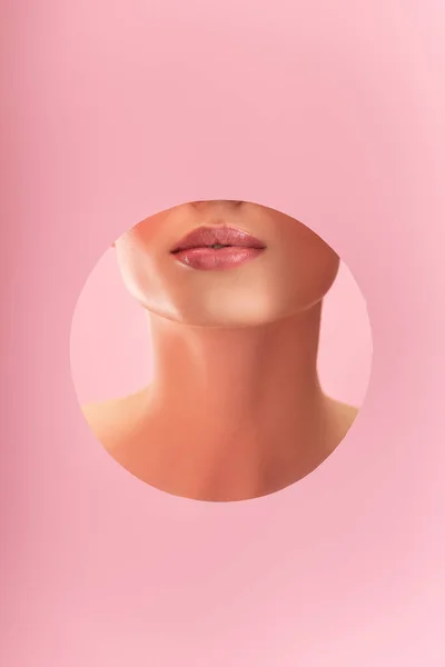 Partial view of beautiful woman with shiny lips in paper round hole isolated on pink — Stock Photo