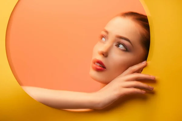 Blurred image of beautiful woman in yellow paper circle hole looking away — Stock Photo