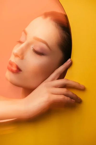 Blurred image of beautiful woman with closed eyes in yellow paper circle hole — Stock Photo