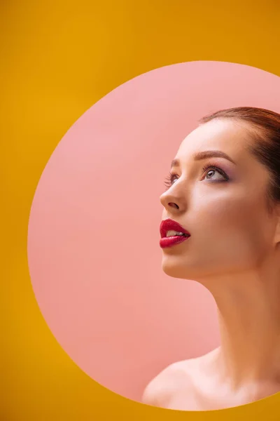 Nu belle femme avec cramoisi lèvres regarder loin à travers jaune trou cercle en papier — Photo de stock