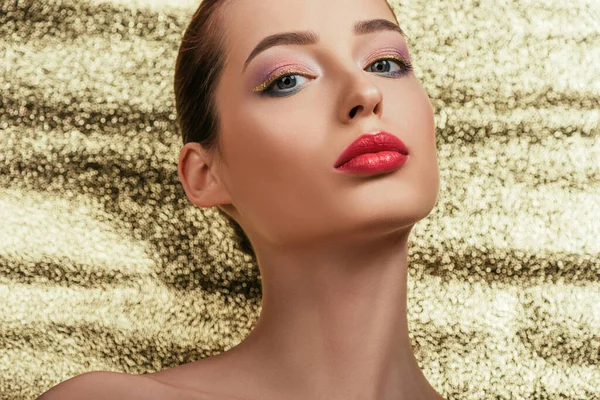 Retrato de mulher bonita nua com maquiagem brilhante olhando para a câmera no fundo dourado — Fotografia de Stock