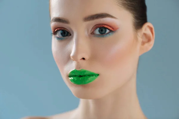 Porträt einer schönen Frau mit grünen Lippen, rosa und blauem Lidschatten isoliert auf blau — Stockfoto