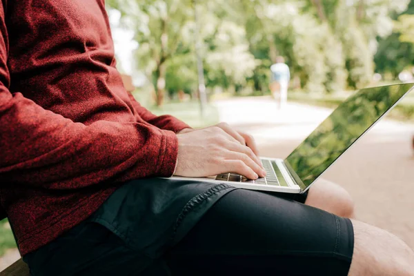 Cropped view of freelancer using laptop in park — Stock Photo