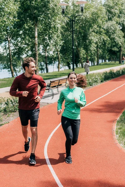 Красивий чоловік посміхається біля дівчини під час бігу в парку — стокове фото