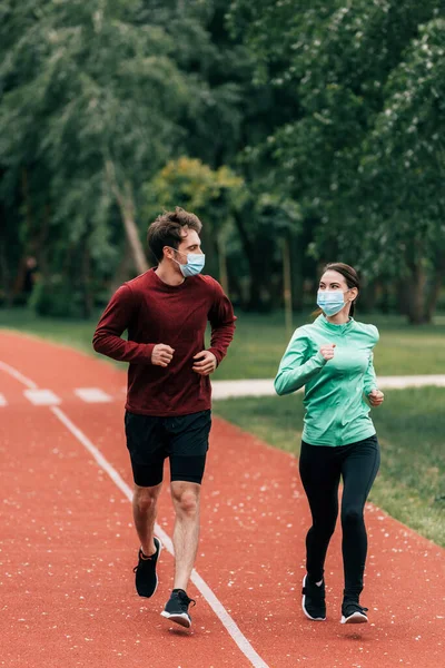 Пара в медичних масках біжить разом на біговій доріжці в парку — стокове фото