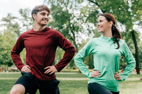 Young couple smiling at each other while training together in park — Stock Photo