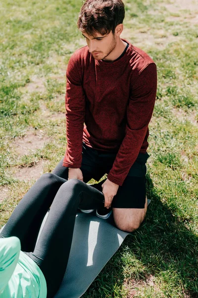 Vue en angle élevé du sportif soutenant la sportive pendant l'entraînement dans le parc — Photo de stock